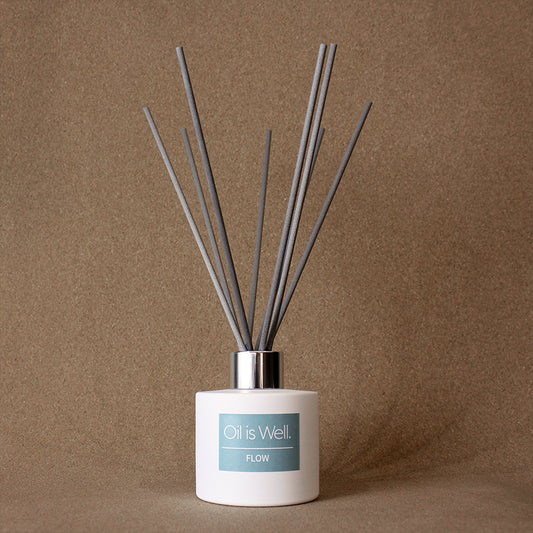 Oil Is Well Flow Reed Diffuser with grey reeds in a chic white bottle, for a calming atmosphere.